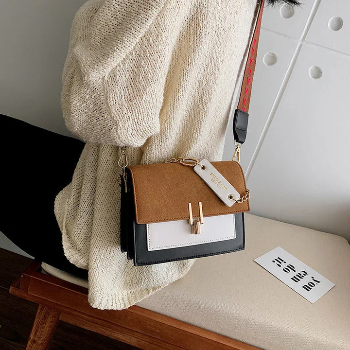 Women wearing cream knit sweater carrying stylish brown, white, and black colorblock crossbody bag indoors