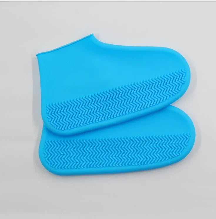 Pair of blue silicone shoe covers with textured anti-slip soles on white background