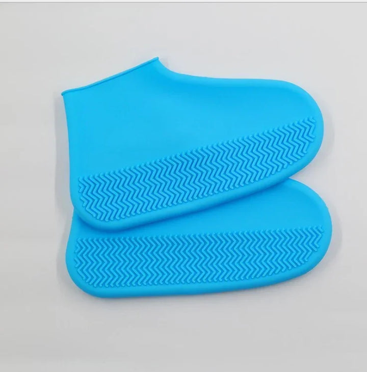 Pair of blue silicone shoe covers with textured anti-slip soles on white background