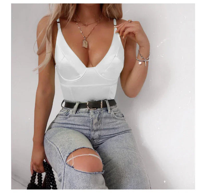 Woman wearing white spaghetti strap top and ripped light blue jeans with black belt, holding black beaded bag