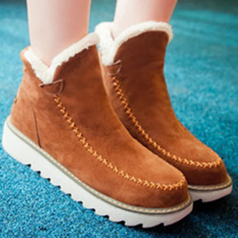Brown suede winter boots with white faux fur lining and thick white soles on blue carpet