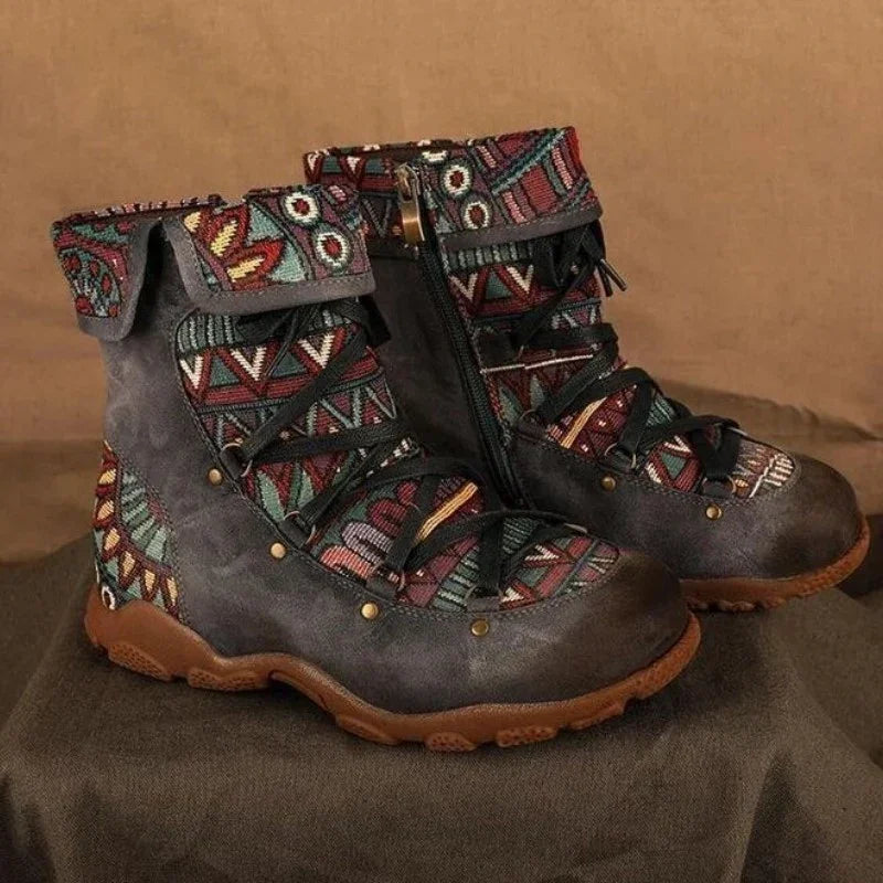 Pair of gray hiking boots with multicolor tribal pattern fabric and brown soles on a brown surface