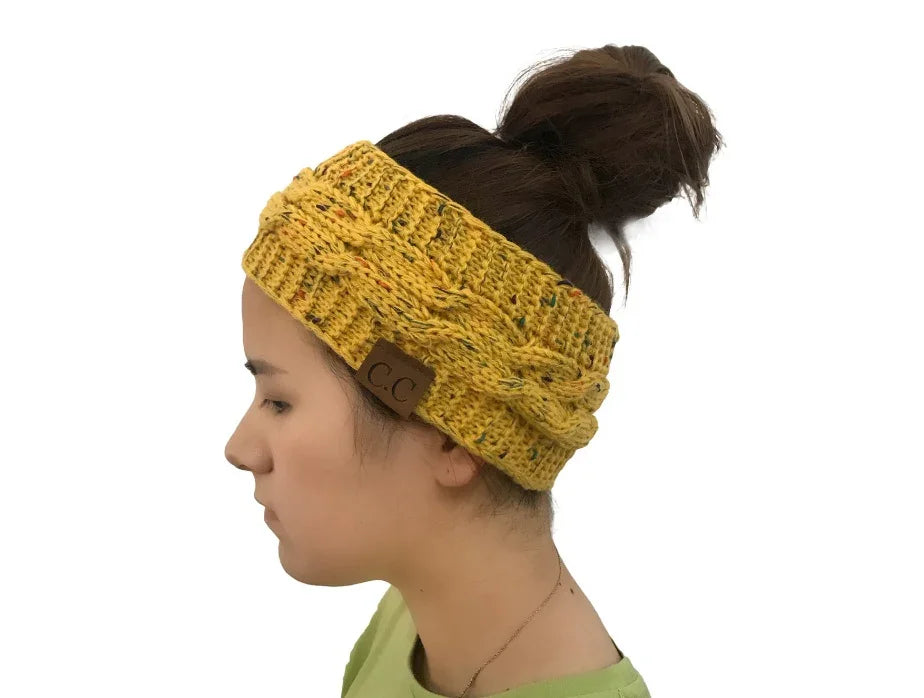 Side view of woman wearing yellow knitted cable winter headband with CC logo tag and hair in bun