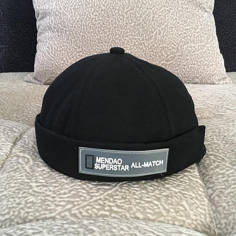 Black men’s casual cap with fold and label reading Mendao Superstar All-Match on patterned fabric background