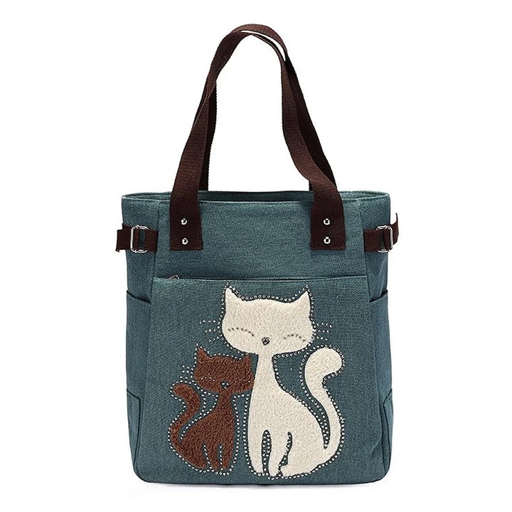Blue tote bag with two embroidered cats and brown fabric handles