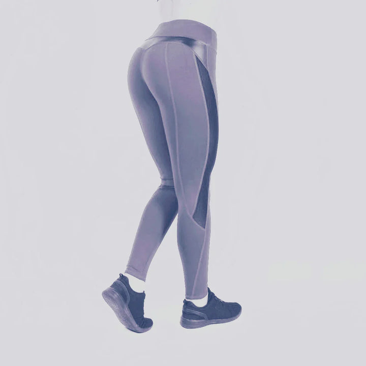 Woman wearing high-waisted purple athletic leggings and black sneakers on white background