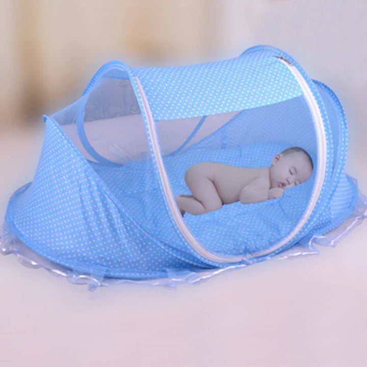 Sleeping baby inside a blue polka dot mesh mosquito net bed