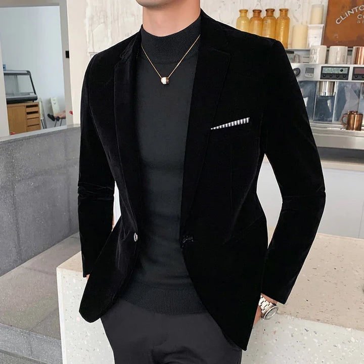 Man wearing black velvet blazer with striped pocket square and black knit turtleneck in modern cafe