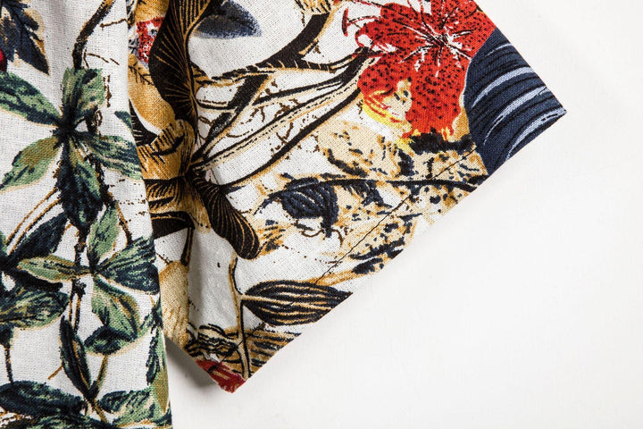 Close-up of fabric with green, black, and red tropical floral print on light background