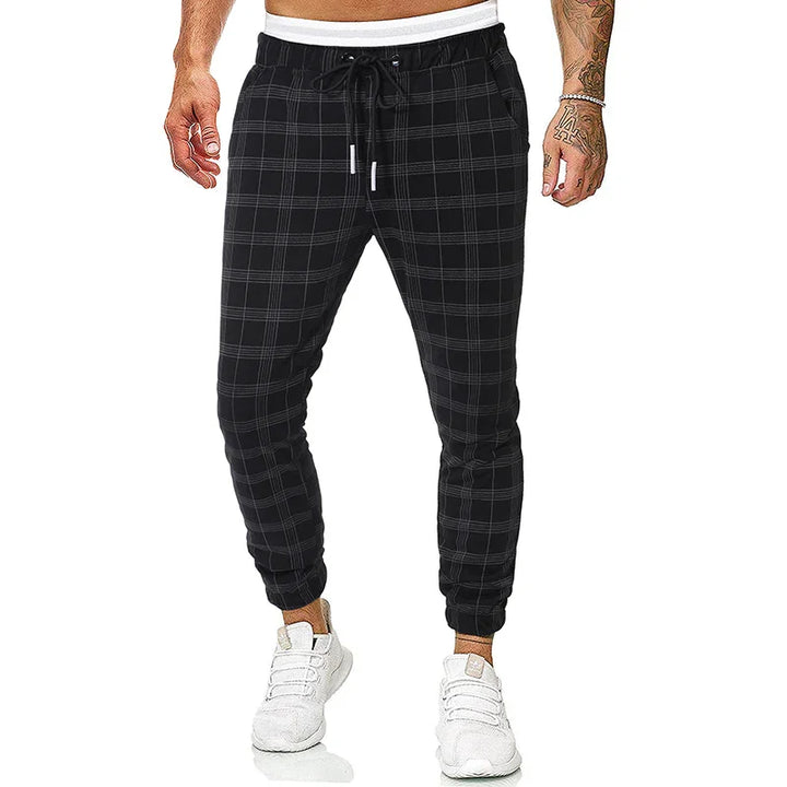 Men's black plaid jogger pants with white drawstring waistband and white sneakers