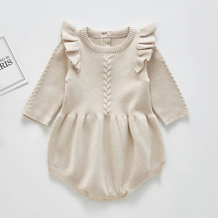Cream knit baby romper with ruffle shoulders and braided cable knit detail on front and sleeves