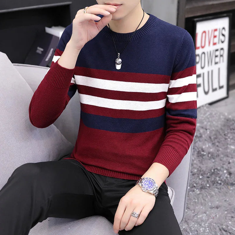 Man wearing maroon, navy, and white striped sweater sitting on a gray couch with accessories