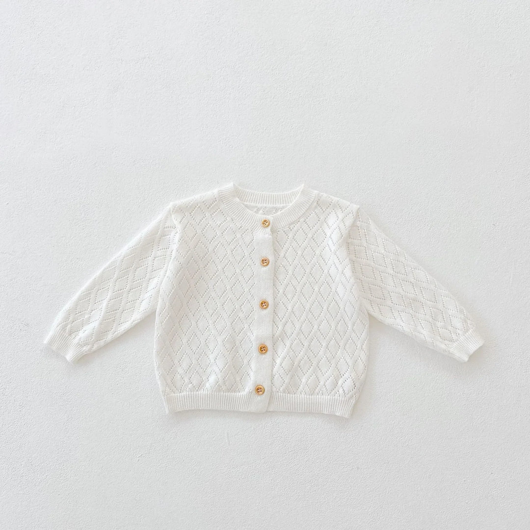 White knitted baby cardigan with diamond pattern and wooden buttons on white background