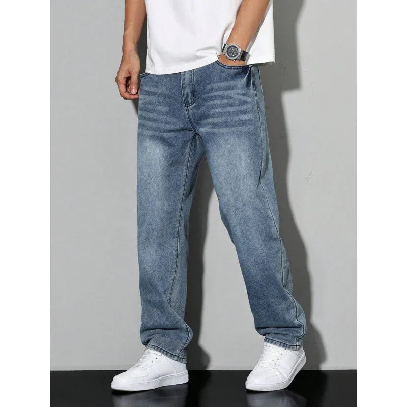 Men's casual blue denim jeans paired with white sneakers and a white t-shirt against gray background