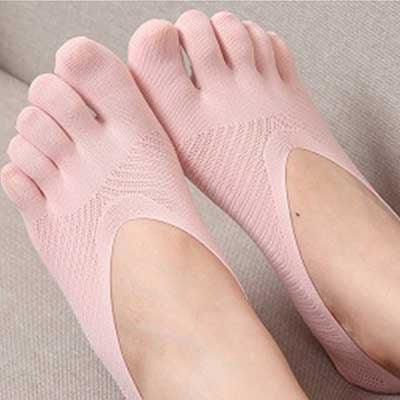 Close-up of feet wearing pink toe socks designed for comfort and flexibility on a beige surface