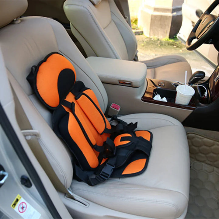 Orange and black children car safety harness installed on beige leather passenger seat
