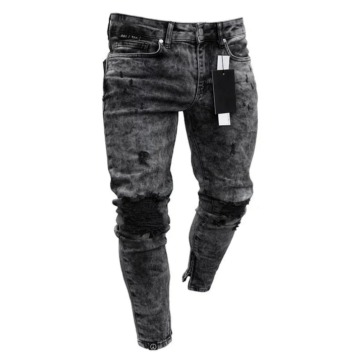 Men's black distressed skinny jeans with knee rips and an attached black tag on white background