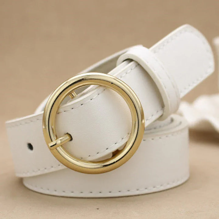 Close-up of white leather belt with round gold buckle on beige background