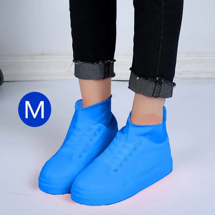 Person wearing medium size blue waterproof silicone shoe covers on black rolled-up jeans