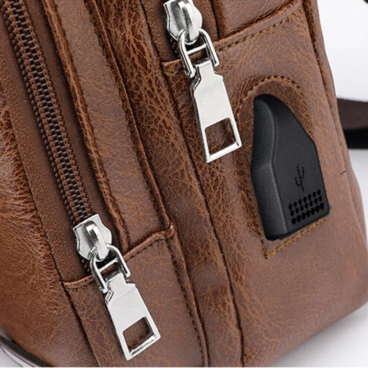 Brown leather bag with silver zippers and a built-in black USB charging port