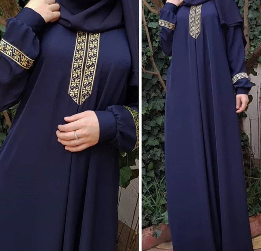 Navy blue abaya with gold embroidered patterns on chest and cuffs, worn outdoors near plants