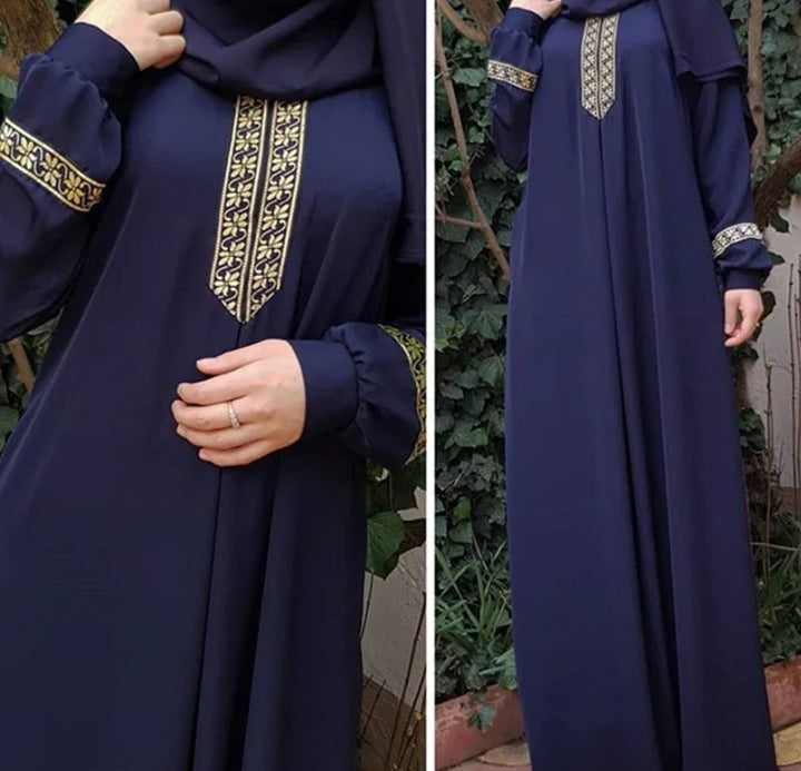 Navy blue abaya with gold embroidered patterns on chest and cuffs, worn outdoors near plants