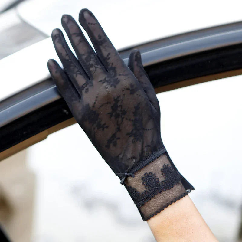 elegant black lace glove with floral pattern and decorative cuff on hand by car window