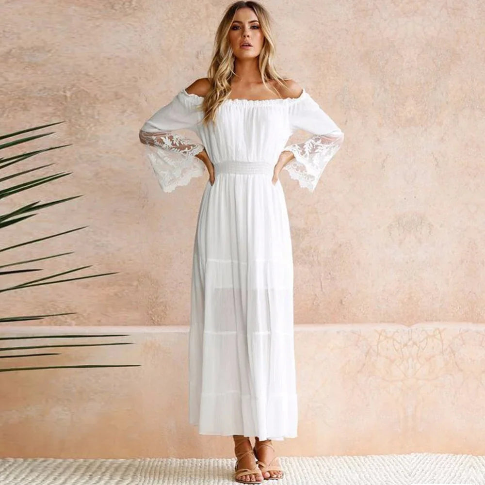 woman in white off-shoulder maxi dress with lace bell sleeves standing against beige textured wall