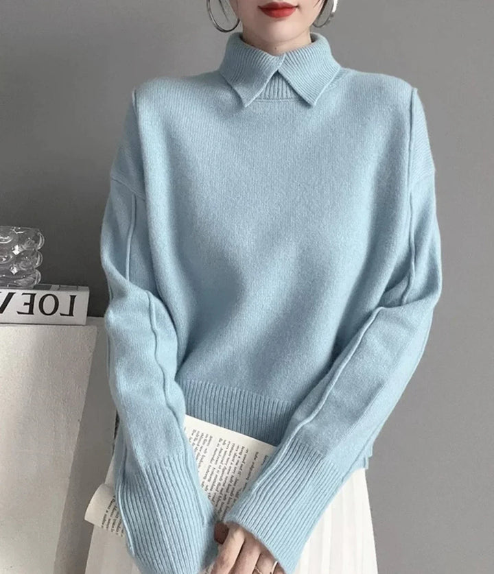 Woman wearing a light blue ribbed sweater with a collar and long sleeves, holding a folded newspaper