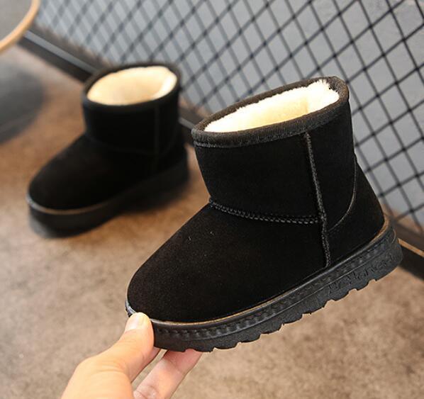 Black suede winter boots with white fleece lining and rugged rubber soles displayed indoors