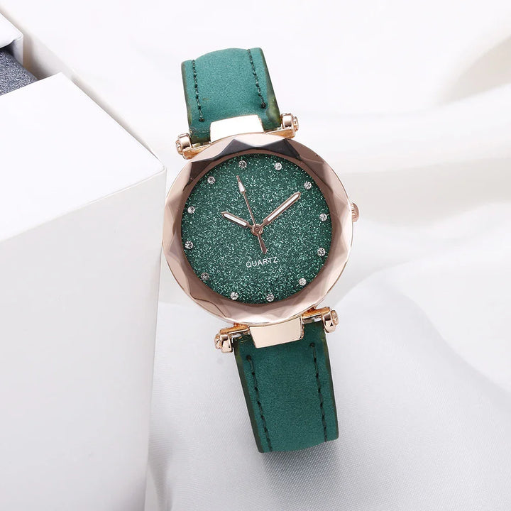 Elegant green quartz wristwatch with glittery dial and gold-tone case on white fabric