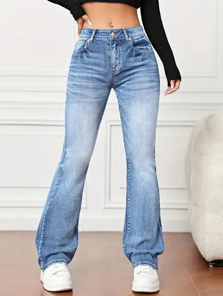 Woman wearing high-waisted blue denim flare jeans with white sneakers and black cropped top