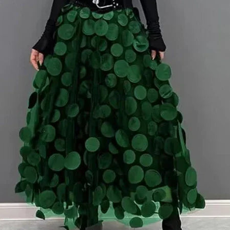 Woman wearing a long dark green skirt with large circular appliques over black top and shoes
