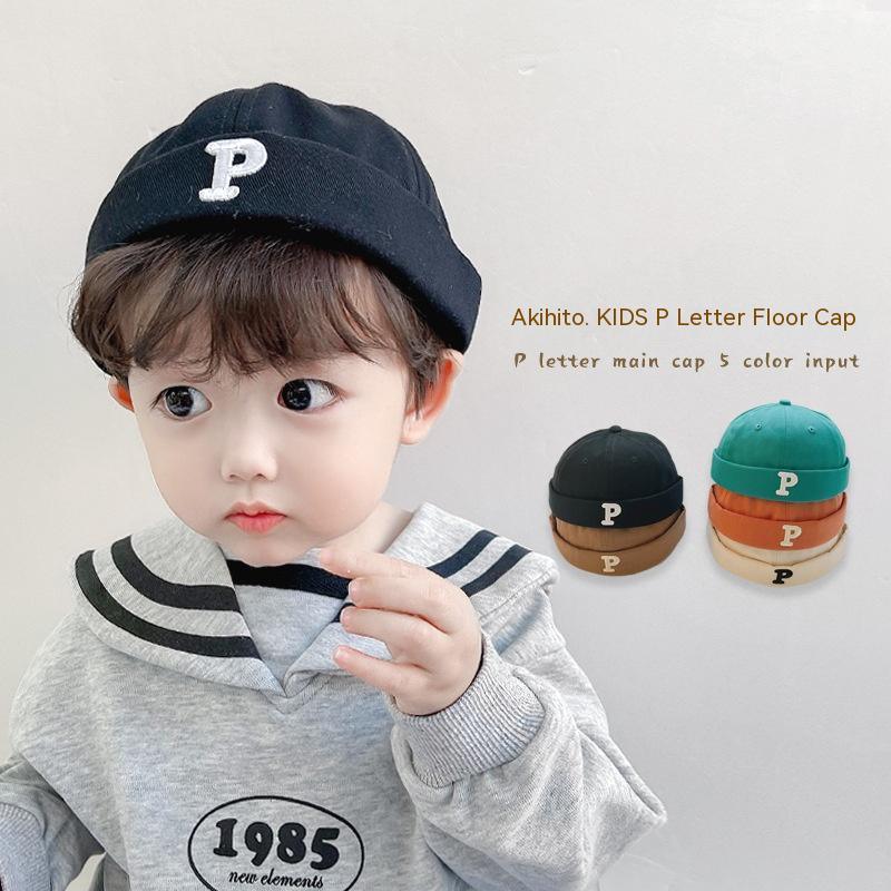 Toddler wearing black kids cap with white P letter, gray sweater, other colorful P letter caps displayed
