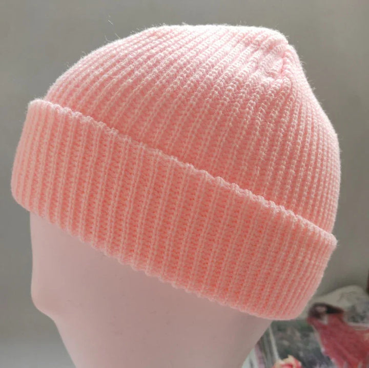 Soft pink ribbed knit beanie hat displayed on a mannequin head against a neutral background