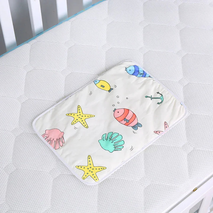 White baby changing pad with colorful sea creatures print on white quilted mattress in crib