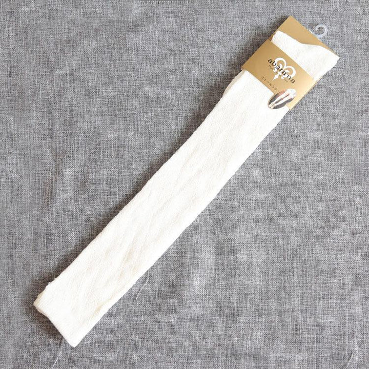 Single white textured sock with beige hanger packaging on gray fabric background