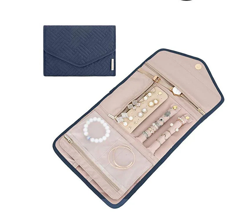 Navy blue fabric jewelry organizer with beige interior holding earrings, rings, bracelets, and a watch