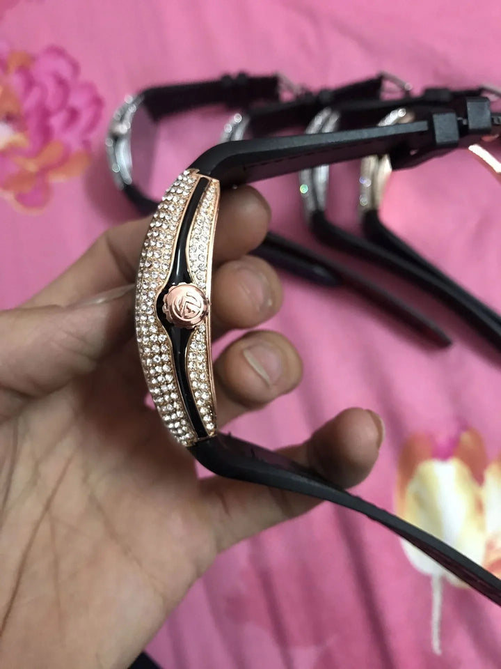 Close-up side view of a black wristwatch with a rose gold-tone bezel encrusted with clear crystals
