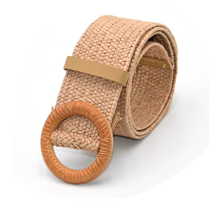 Beige woven fabric belt with a round wooden buckle and leather loop, rolled up on white background