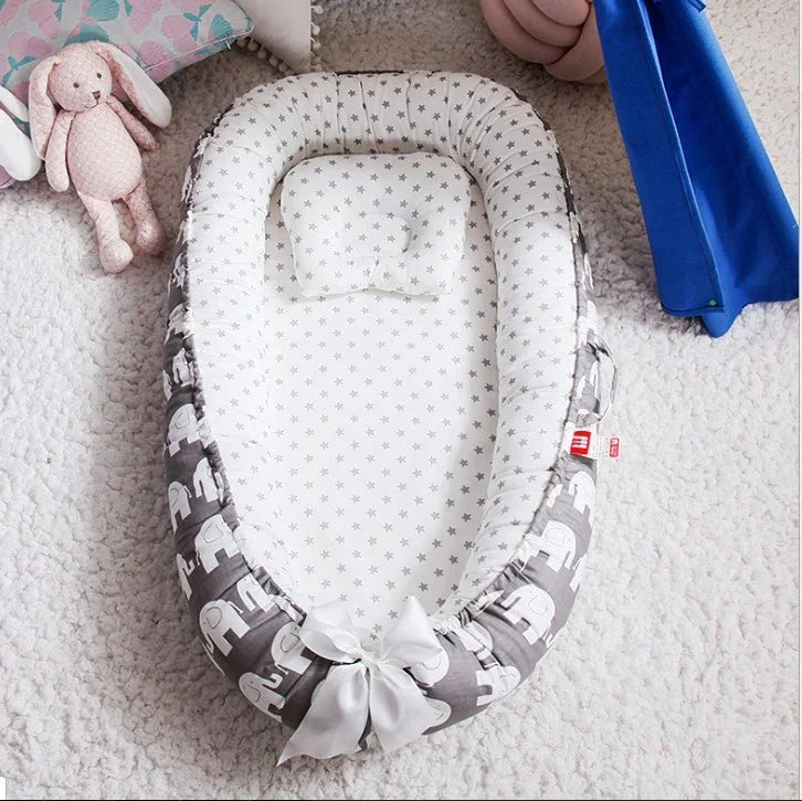 Baby lounger with gray elephant print and star-patterned interior on a soft white rug