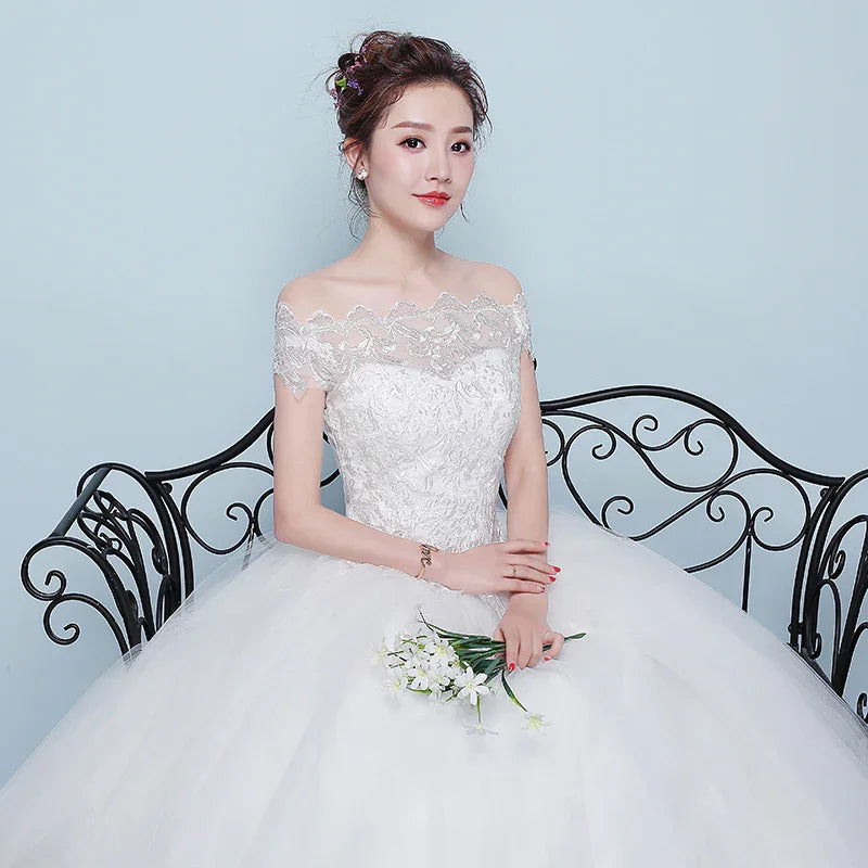 Bride in white lace off-shoulder wedding dress sitting on ornate black wrought iron bench holding white flowers