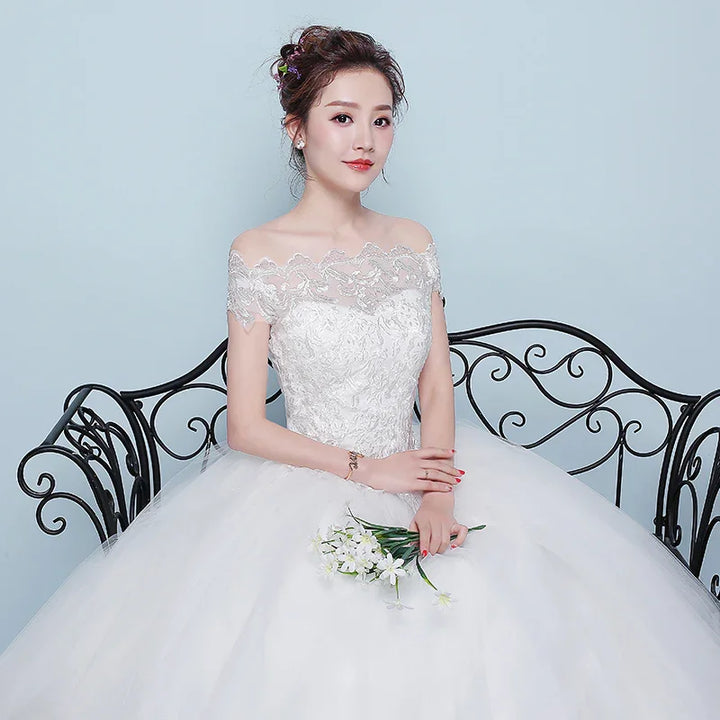 Bride in white lace off-shoulder wedding dress sitting on ornate black wrought iron bench holding white flowers