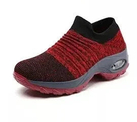 Red and black knitted slip-on athletic shoe with cushioned gray sole and air bubble