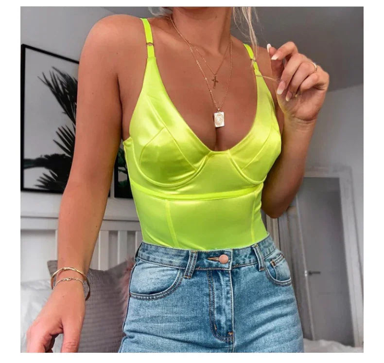 Woman wearing neon yellow satin camisole and high-waisted light blue denim jeans in modern indoor setting