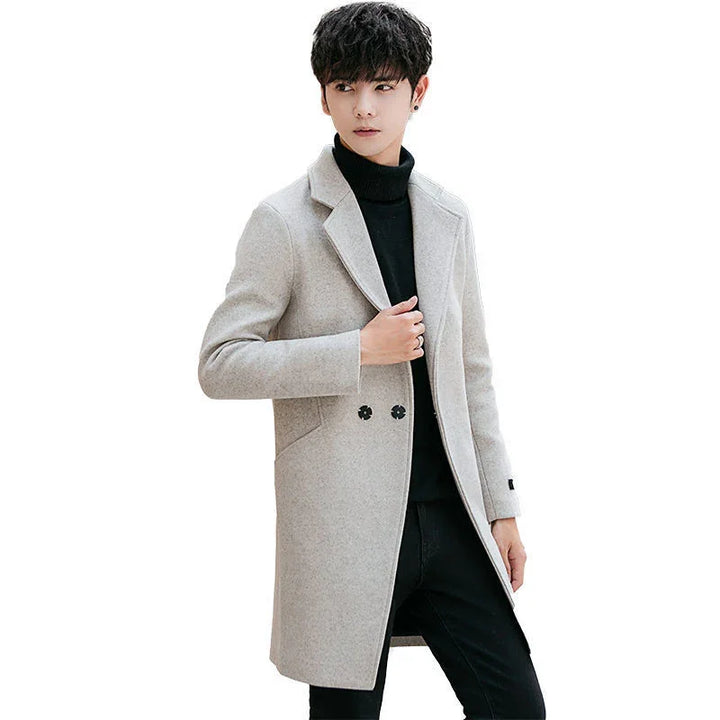 Young man wearing stylish light gray wool coat over black turtleneck and black pants on white background