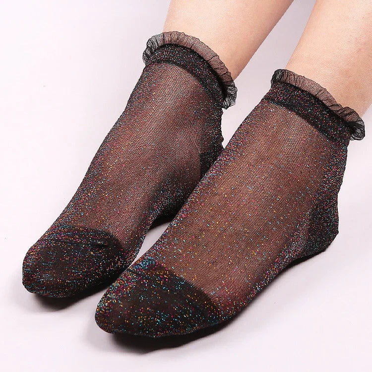 Pair of black sheer ankle socks with multicolor glitter and ruffle edges on feet