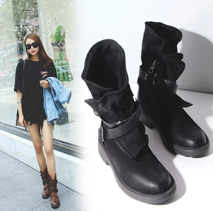 Stylish woman wearing black oversized shirt and brown slouchy leather boots, holding denim jacket, standing outside