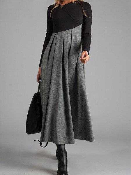 woman wearing black and grey long sleeve pleated maxi dress with black boots and carrying black bag