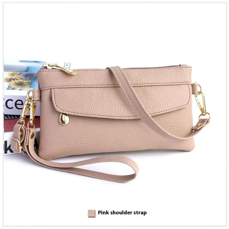 Beige textured leather wristlet clutch with gold hardware and detachable pink shoulder strap